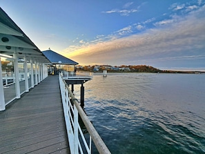 A waterfront pier with a covered seating area and a view of the water and distant buildings. - Double room 24 - Domkes Hotel Garni Haus an der See (Heringsdorf)