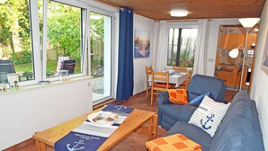 A cozy living room with a blue sofa, wooden coffee table, and a dining table with chairs.