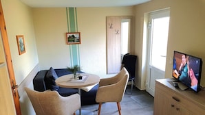 Un salon confortable avec une table ronde, deux chaises, un canapé, un téléviseur et un meuble.