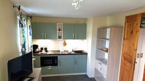 Une cuisine compacte avec des meubles de couleur turquoise, un four encastré et une porte en bois.