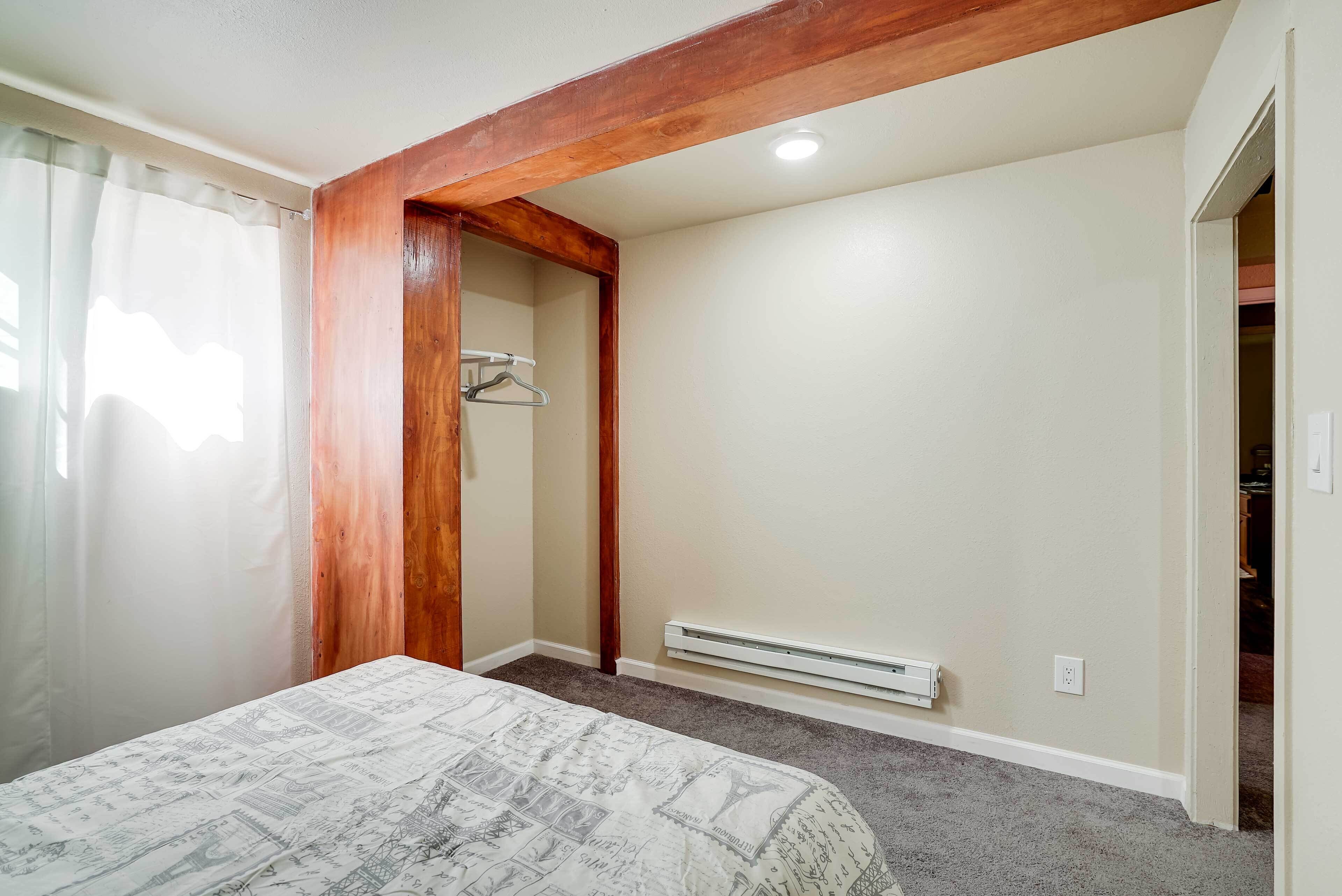 A bedroom with a bed, a wooden ceiling beam, a radiator, and a closet.