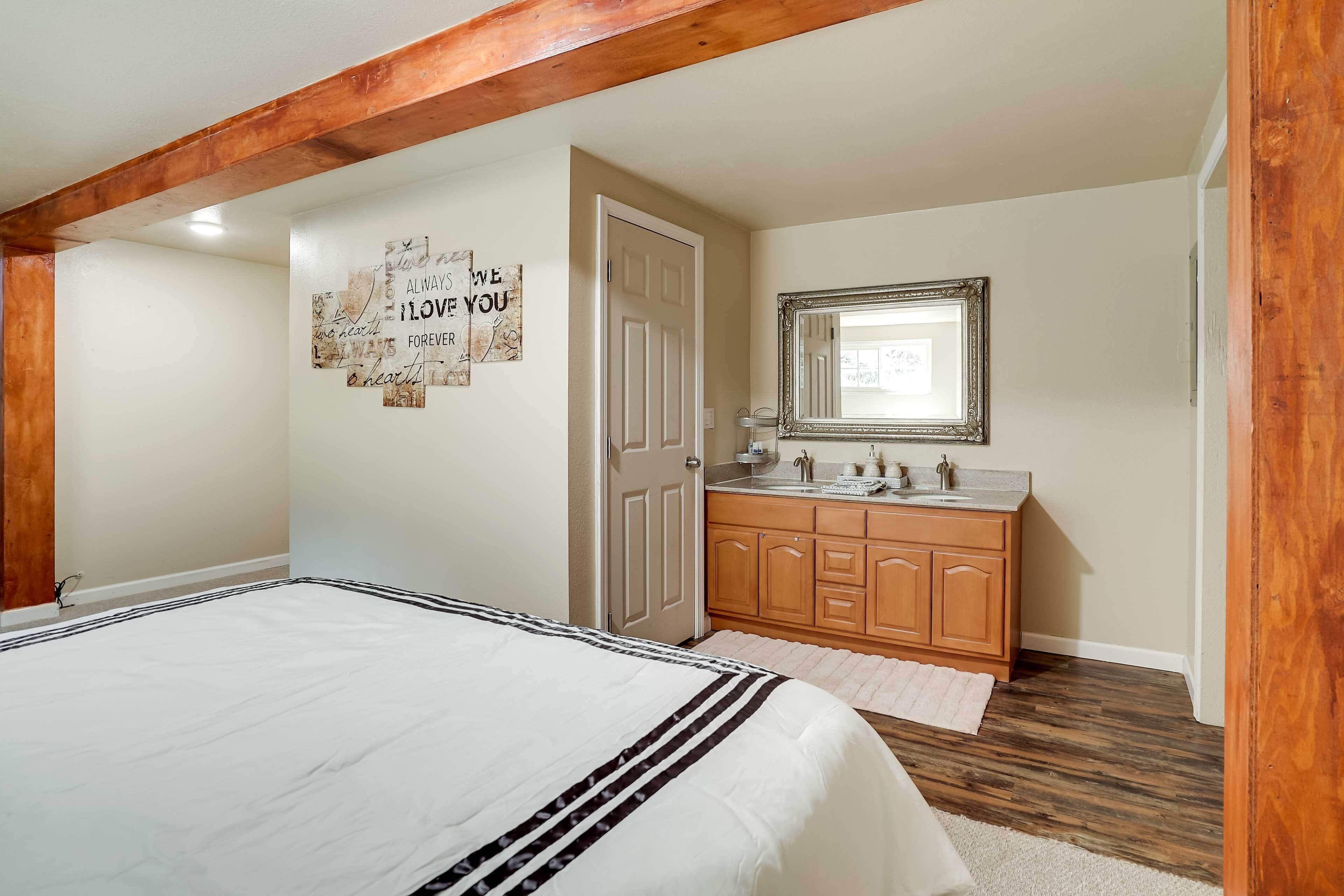 Un dormitorio con una cama grande, vigas de madera, un baño con tocador de madera y un espejo.
