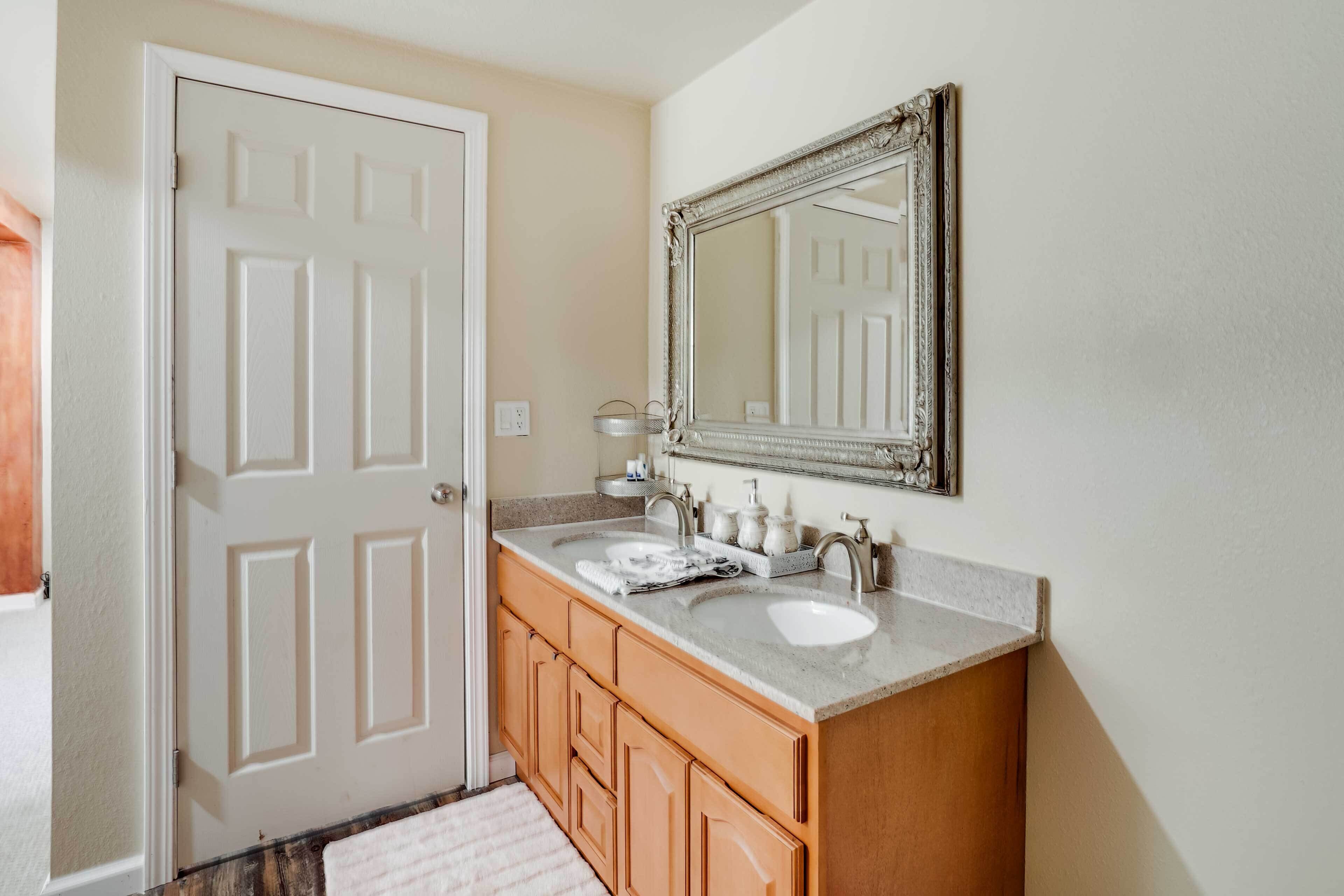 Une salle de bain avec un meuble-lavabo à deux vasques, un grand miroir et des armoires en bois.