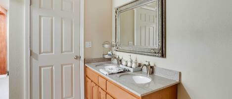 Une salle de bain avec un meuble-lavabo à deux vasques, un grand miroir et des armoires en bois.