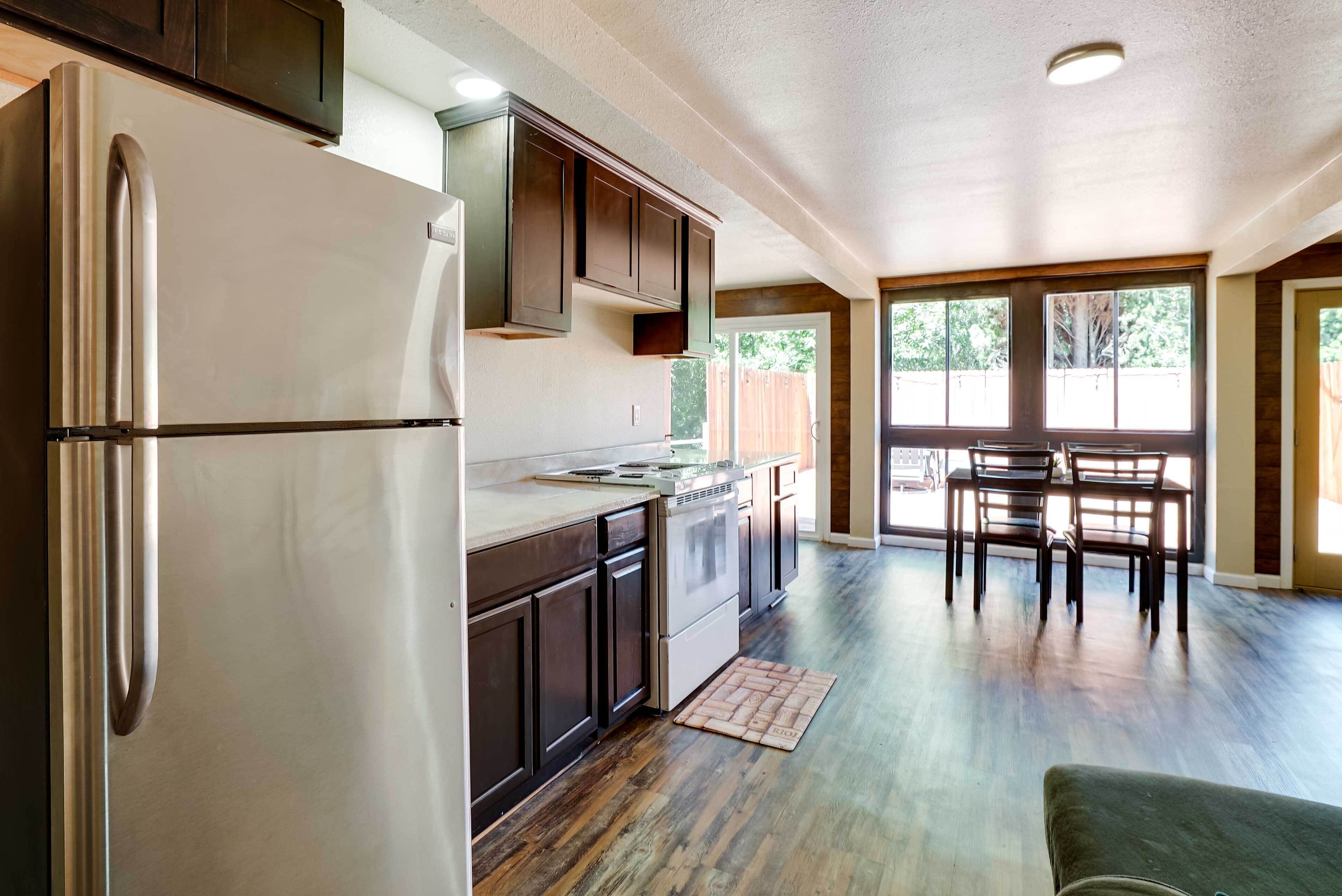 A modern kitchen with dark cabinets, stainless steel appliances, and a dining area with a wooden table and chairs.