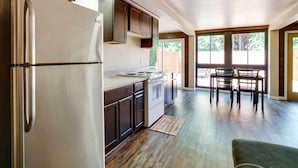 A modern kitchen with dark cabinets, stainless steel appliances, and a dining area with a wooden table and chairs. - Unique Castro Valley House 30 Mi to San Fran! (Castro Valley)