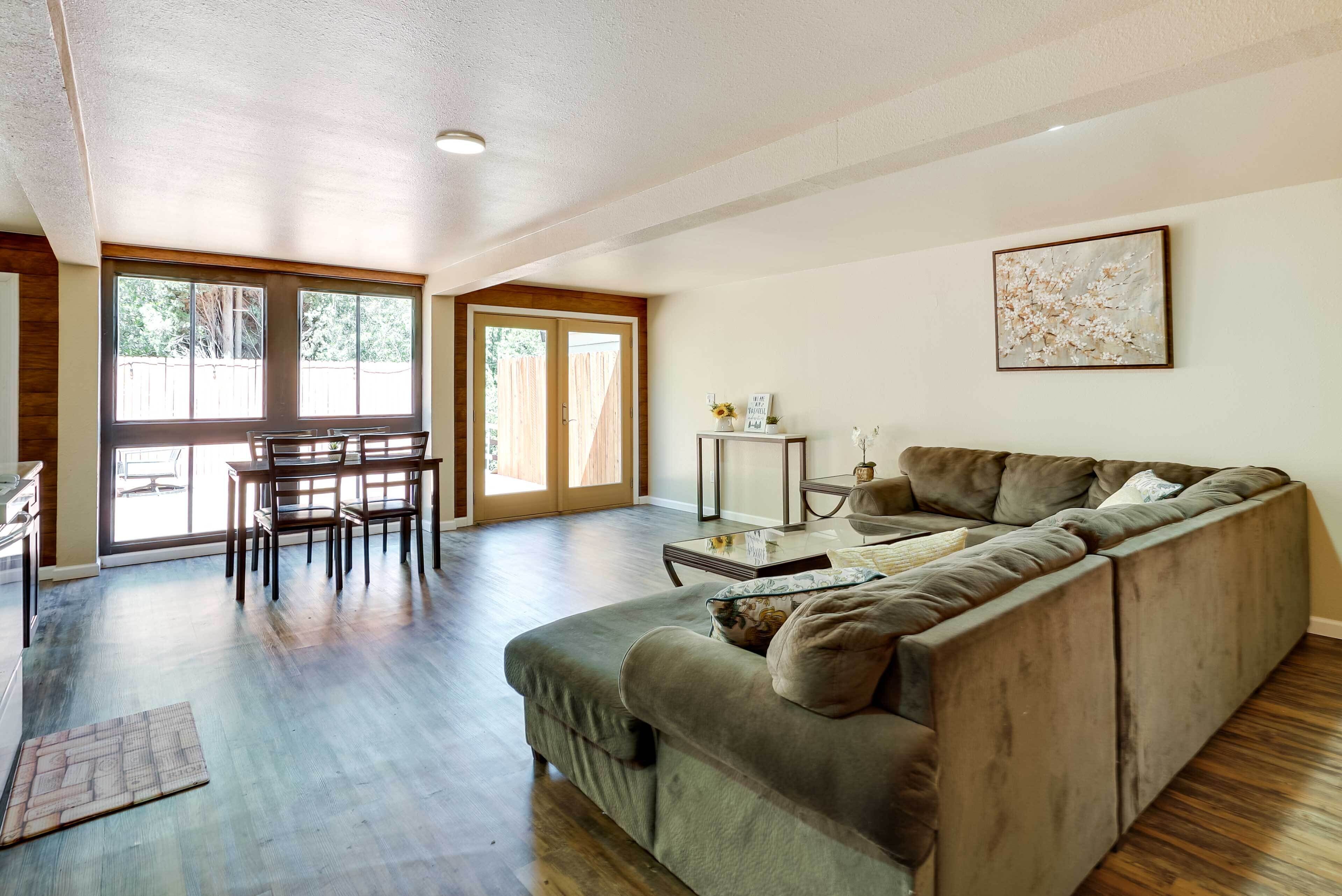 A spacious living area with a large sofa, a dining table with chairs, and a small side table.