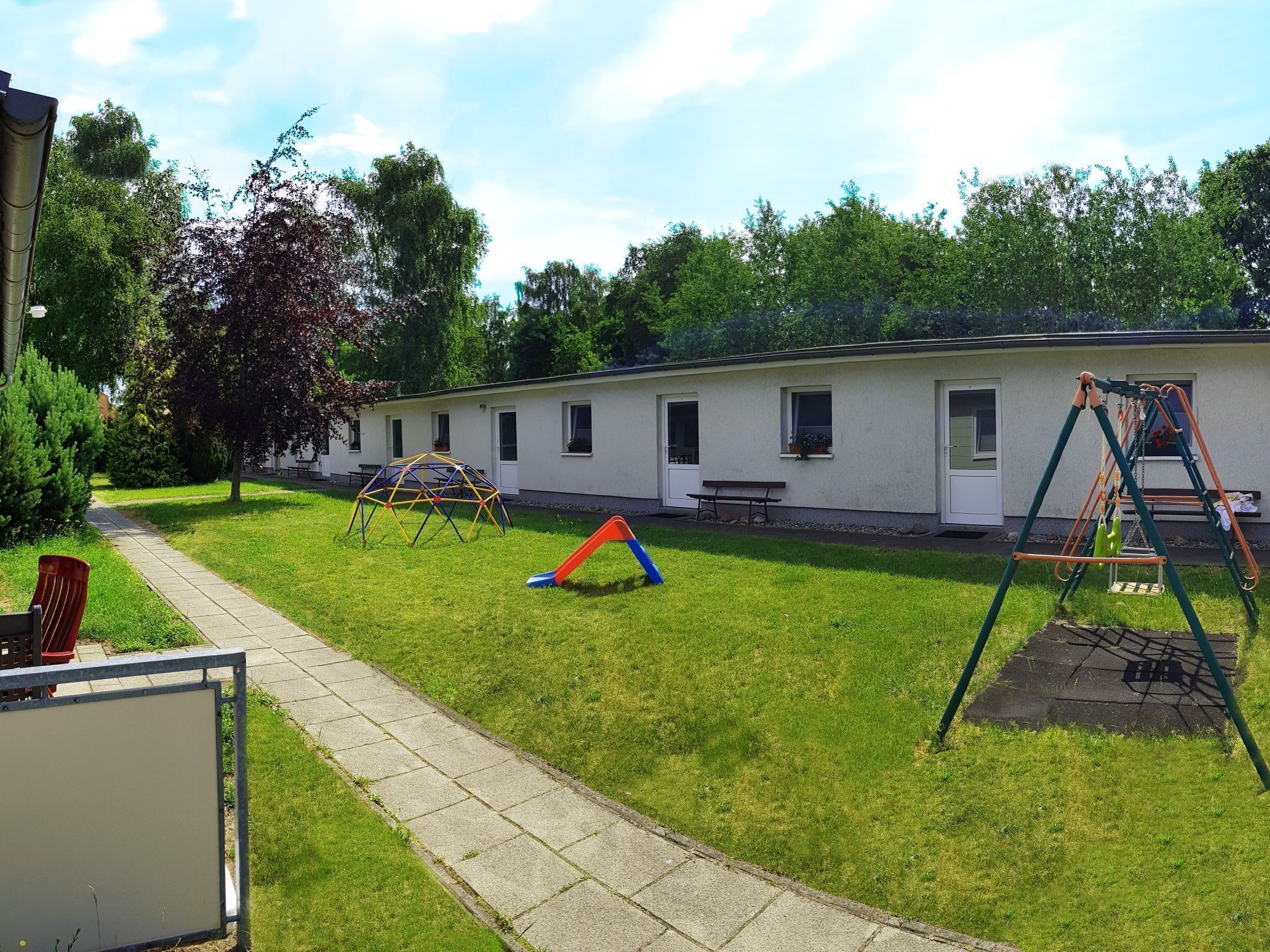 A grassy area with playground equipment, a picnic table, and a building with windows.