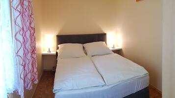 A double bed with white linens, two bedside lamps, and a wooden headboard.
