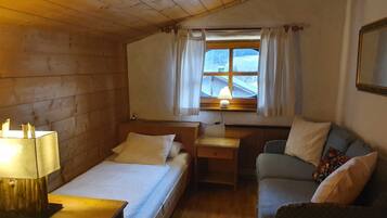 Ein gemütliches Zimmer mit Bett, Schreibtisch, Stuhl und einem fenster mit Vorhängen.
