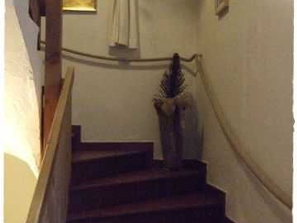 A staircase with a handrail, a wall with a window, and a door at the top.