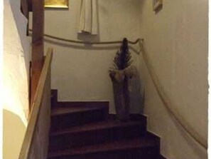 Una escalera con barandilla, una pared con ventana y una puerta al final.