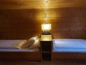 A wooden cabin room with a single bed, a nightstand with a lamp, and a wooden ceiling. - Apartment 4 - Apartment Pension Bäckenhäusl (Uttendorf)