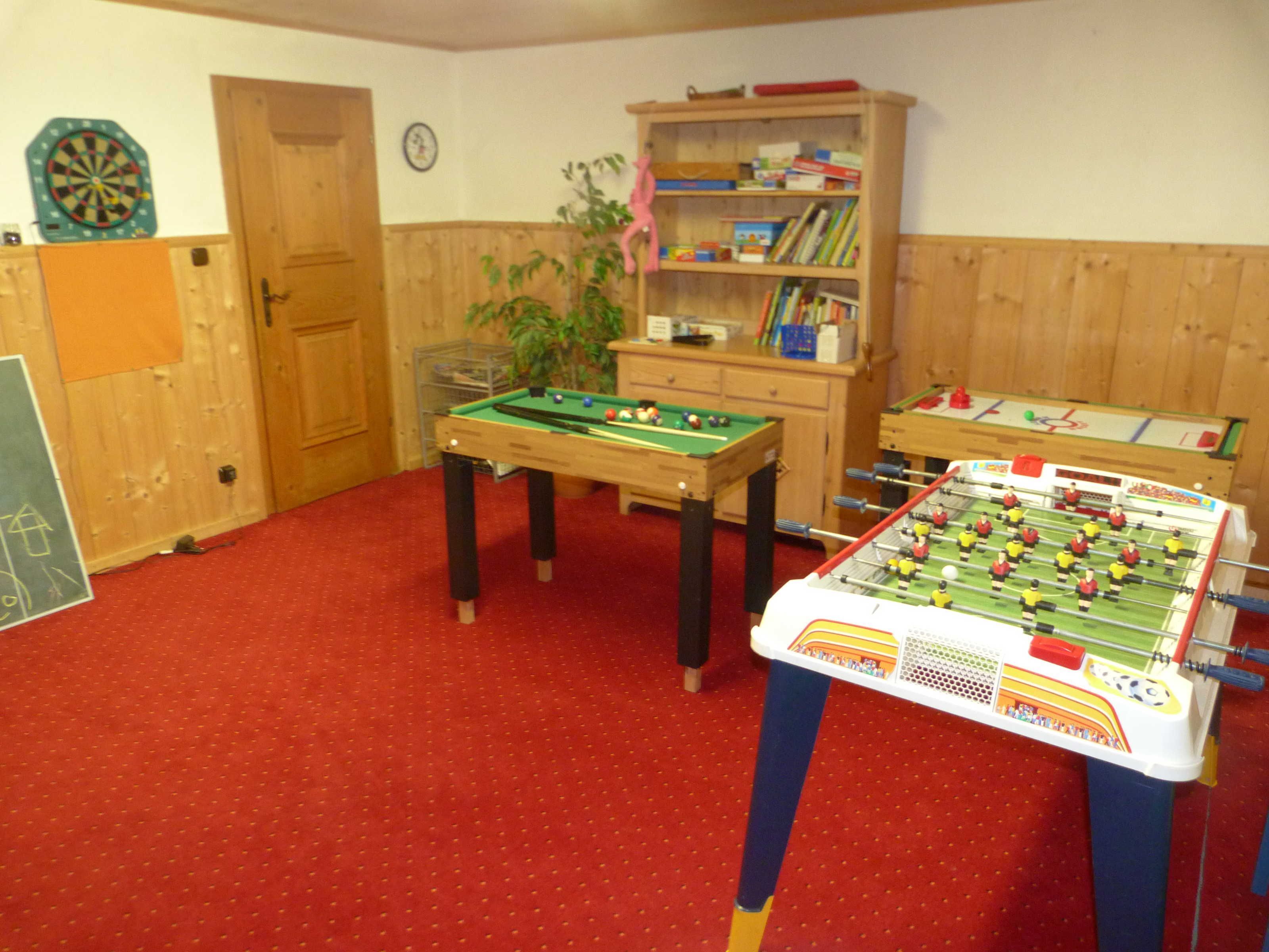 Una habitación con mesa de fútbol, mesa de billar y dardos.