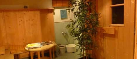 Een houten interieur met een ronde tafel, een potplant en een raam.