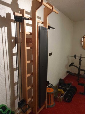 A home gym with a pull-up bar, a bench press, and weight plates. - Apartment 4 - Apartment Pension Bäckenhäusl (Uttendorf)