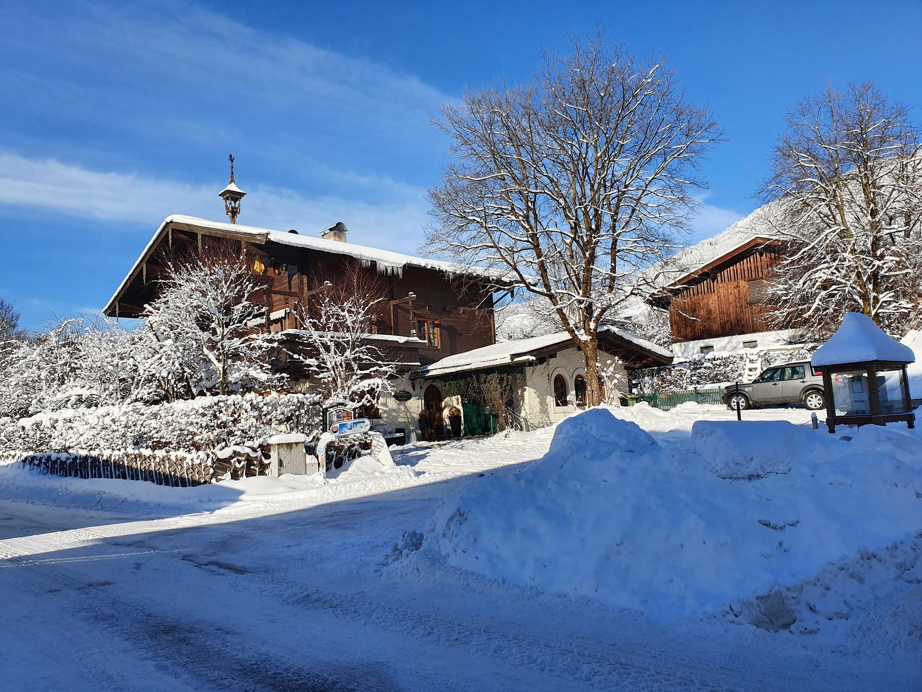 Un pueblo cubierto de nieve con casas de madera tradicionales, cielo despejado y un camino nevado.
