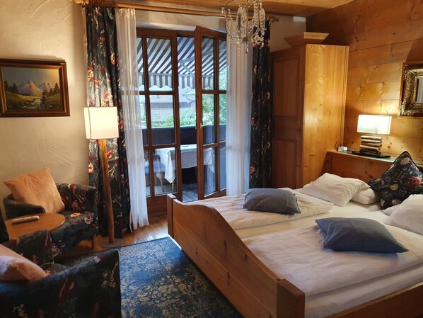 Una habitación de madera con una cama, una silla, una mesa y vistas a través de una ventana.