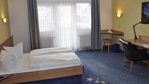 Une chambre d’hôtel avec un lit, un bureau, une chaise et une lampe.