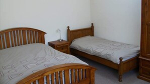 A bedroom with two wooden beds, a nightstand, and a wardrobe.