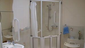 A bathroom with a shower enclosure, a sink, and a mirror.
