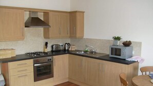A kitchen with wooden cabinets, a gas stove, an oven, a microwave, and a sink.