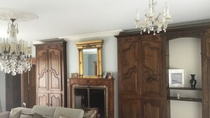 Una sala de estar con un sofá, armarios de madera, una chimenea y una araña.