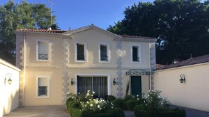 Un edificio de dos pisos con fachada simétrica, una entrada central con puerta verde y un camino de entrada de grava.