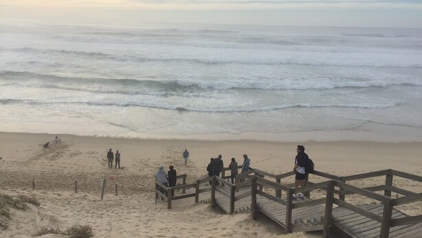 Una playa con un paseo marítimo de madera que conduce a la orilla.