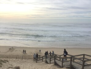Una playa con un paseo marítimo de madera que conduce a la orilla.