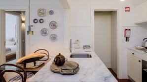 Eine moderne Küche mit Marmorarbeitsplatte, Spüle und Herd. An der Wand befinden sich dekorative Teller und ein Holzschneidebrett mit Teekanne auf der Arbeitsfläche.