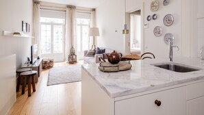Eine moderne Küche mit Marmorarbeitsplatte, einer Spüle und einem Essbereich inklusive Sofa und Lampe.