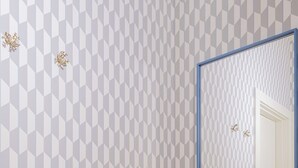 Ein Badezimmer mit Wand in geometrischem Muster, einem Spiegel und Holzboden.