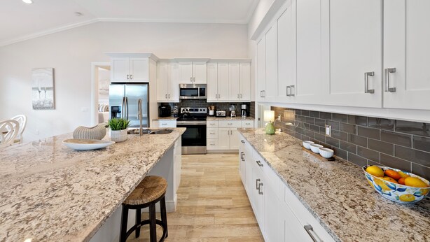 A modern kitchen with white cabinets, granite countertops, and stainless steel appliances. - Beautiful New Marco Island Home Minutes to Beaches, Parks & Restaurants (Marco Island)