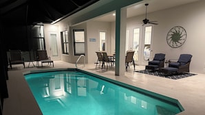 A swimming pool with a clear blue water, surrounded by lounge chairs and a dining area. - Beautiful New Marco Island Home Minutes to Beaches, Parks & Restaurants (Marco Island)