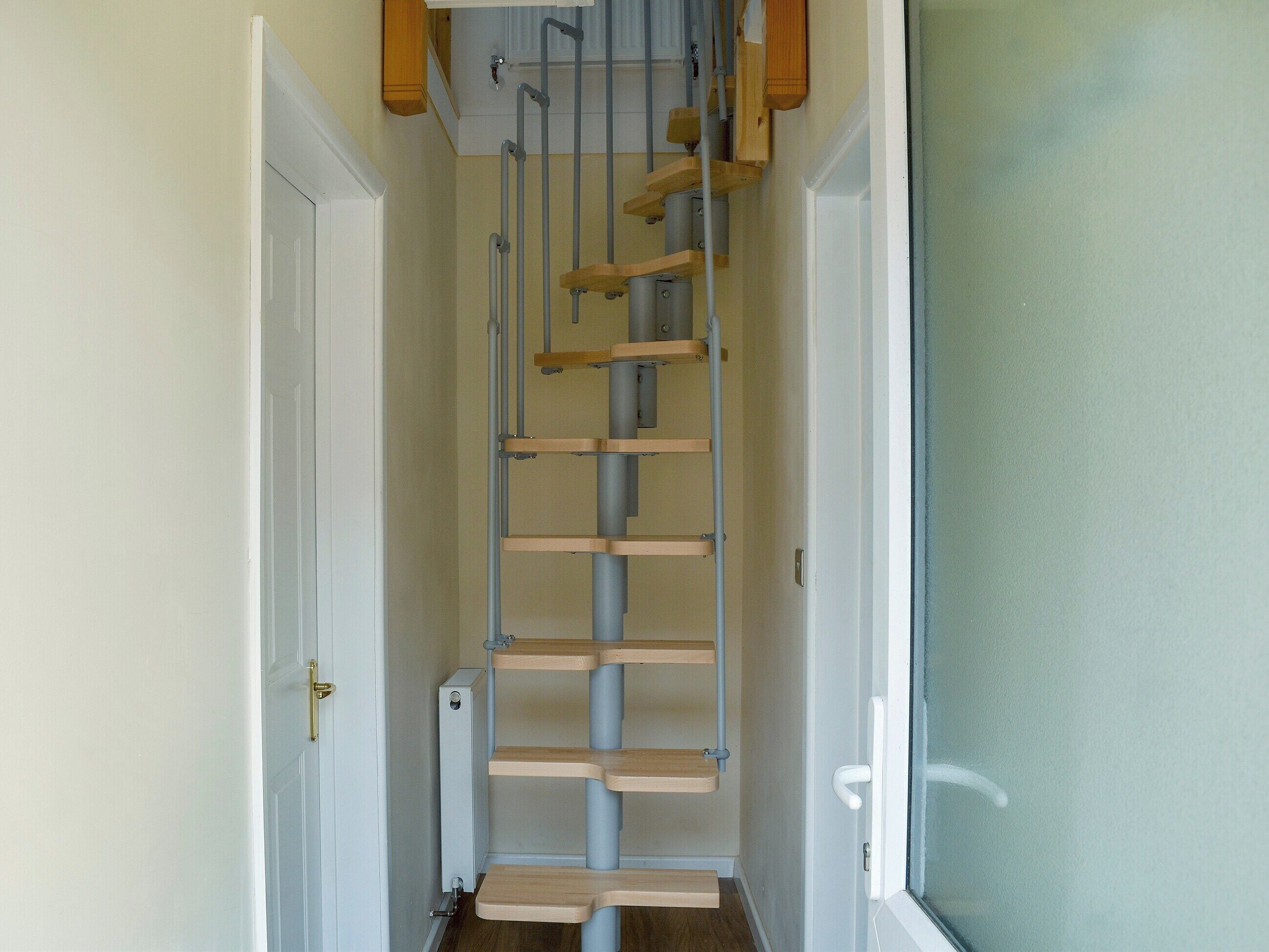 Un couloir étroit avec une échelle en bois menant à une porte.