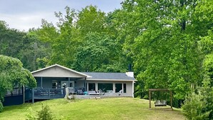 Une maison avec un patio couvert, un quai et un petit bateau.