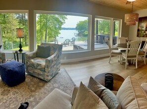 Relax in this serene space with a view of the lake and surrounding greenery, featuring a comfortable seating area and dining space.