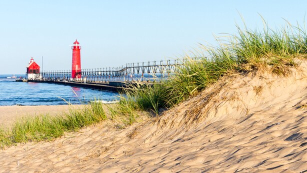 A coastal scene with a red lighthouse and pier extending into the water. - Two bed two bath plus loft condo in Grand Haven (Grand Haven)