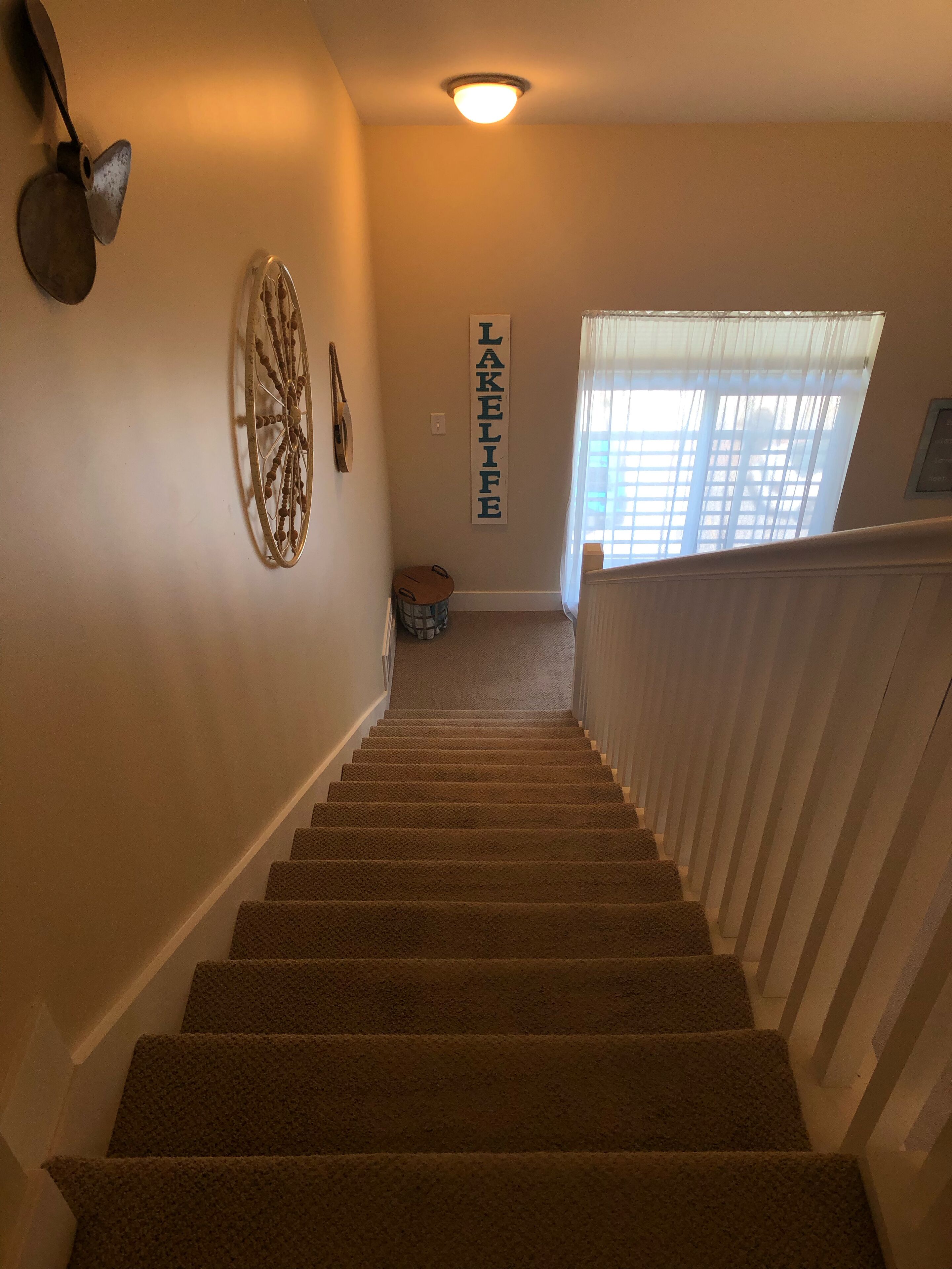 Un escalier recouvert de moquette, avec une enseigne fixée au mur portant l’inscription « LAKELIFE ».