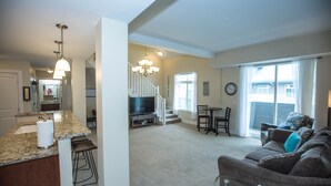 A spacious living area with a large couch, a dining table, and a kitchen with granite countertops. - Two bed two bath plus loft condo in Grand Haven (Grand Haven)