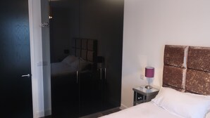 A hotel room with a bed, a nightstand, a lamp, a wardrobe, and a door. - Grand Canal Dock Corporate Apartment (Dublin)