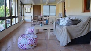 Een ruim balkon met een bank, poefs en een tafeltje.