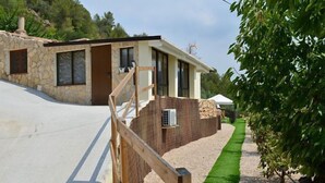 Een modern gebouw met een gevel van natuursteen, een houten terras en een groen gazon.