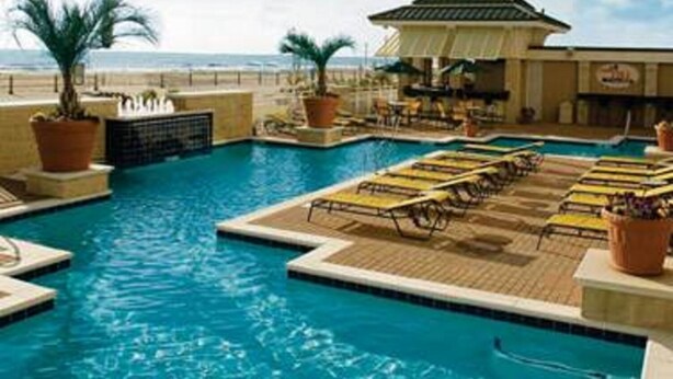 A pool area with multiple sections, lounge chairs, and potted plants.