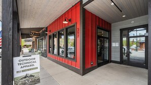A storefront with a red exterior and large windows, featuring an 'OUTDOOR TECHNICAL APPAREL' sign. - Modern Condo in Downtown Whitefish, Prime Location (Whitefish)