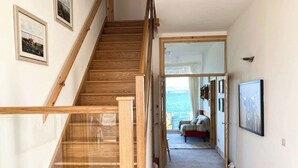 A wooden staircase leading to a bedroom with a view of the sea.