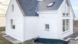 A white two-story house with a sloped roof, a chimney, and a small skylight.