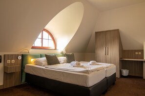 A bedroom with a bed, a window, a wardrobe, and a desk.
