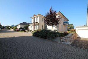 Une rue résidentielle bordée de maisons, avec une allée pavée et un arbre.